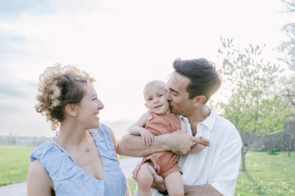 father kisses young son's cheek as mother watches 
